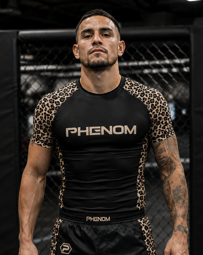 A man wearing a black and leopard-print Phenom rash guard and matching black rash guard shorts with leopard-print side panels, standing in an MMA ring.