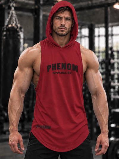 A muscular man wearing a red sleeveless hooded tank top with 'PHENOM APPAREL CO.' printed in black across the chest, standing in a gym setting.