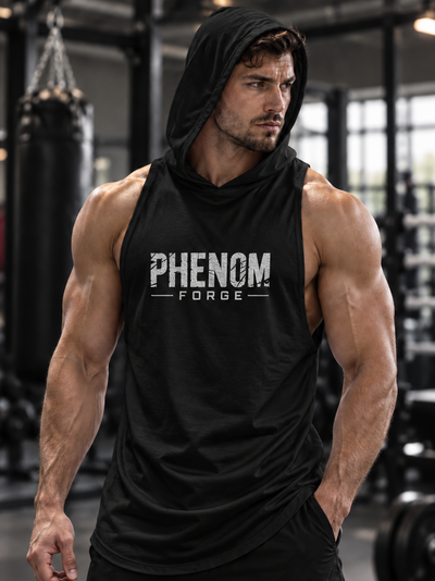 A muscular man in a gym wearing a black sleeveless hooded tank top with 'PHENOM FORGE' printed in white across the chest, paired with black shorts.