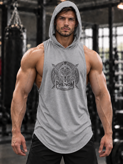 A muscular man wearing a gray sleeveless hooded tank top with a black graphic print on the chest that reads 'PHENOM' and 'Gymnasium'. The background is a gym with a desaturated, black-and-white effect, making the product stand out.