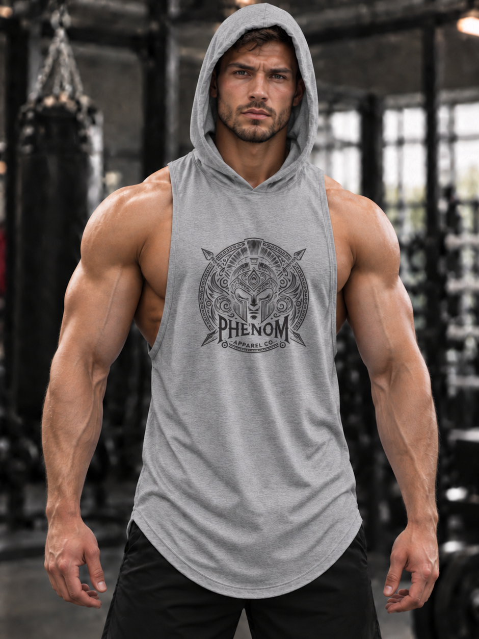 A muscular man wearing a gray sleeveless hooded tank top with a black graphic print on the chest that reads 'PHENOM' and 'Gymnasium'. The background is a gym with a desaturated, black-and-white effect, making the product stand out.