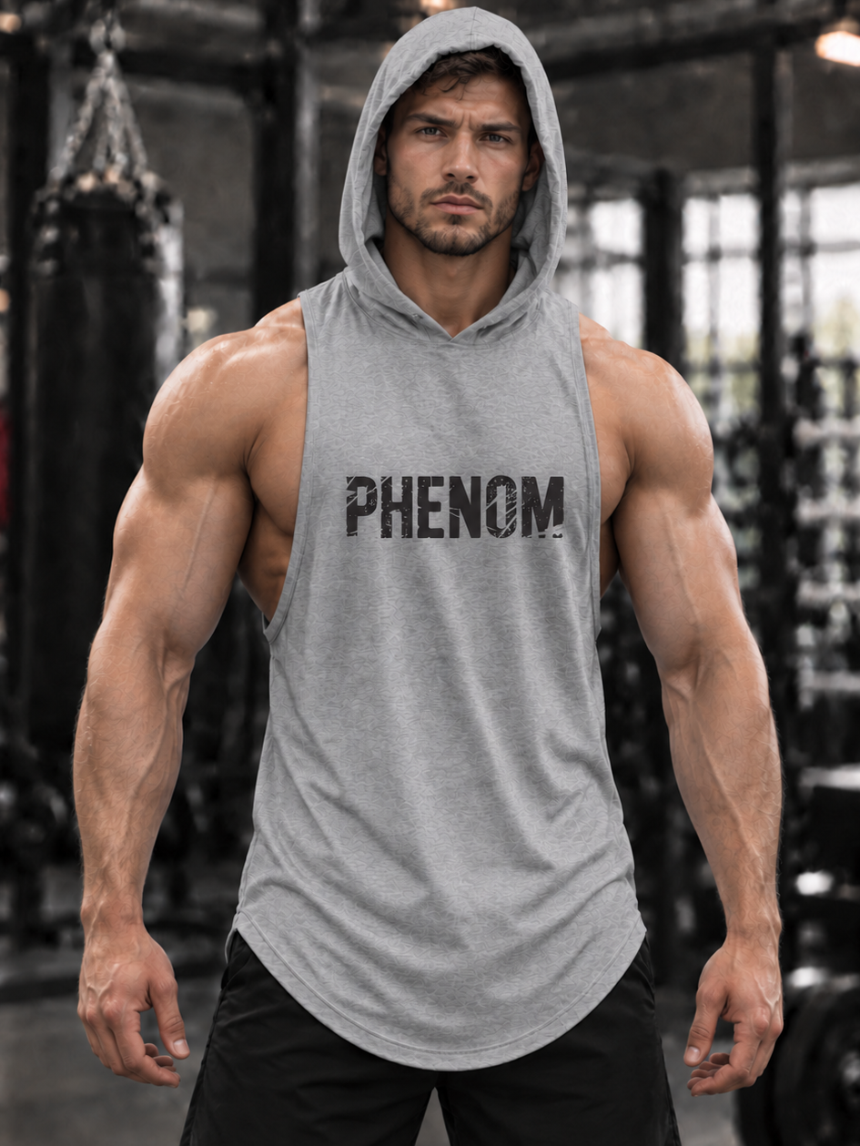 A muscular man wearing a gray sleeveless hooded tank top with the word 'PHENOM' printed across the chest, standing in a gym with a black background.